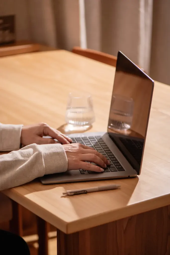 person working on laptop at wooden desk showing blog flipping workflow