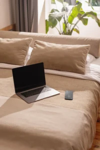 laptop on bed with notebook showing relaxed blog flipping workspace